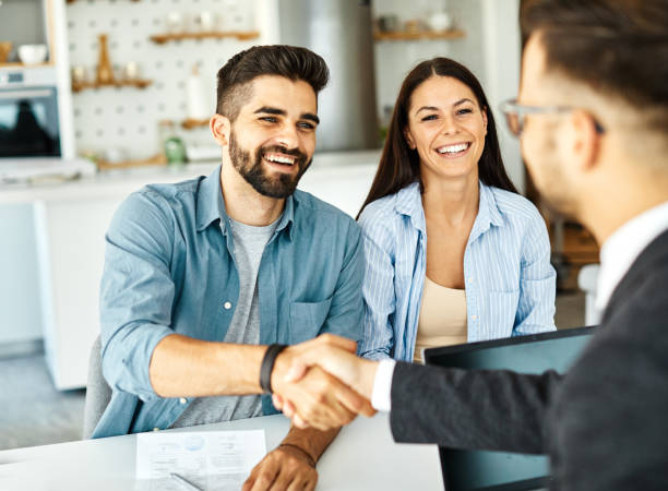 Real estate agent with couple shaking hands closing a deal and signing a contract